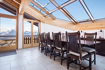 A dining room with a table and chairs and a view of the mountains