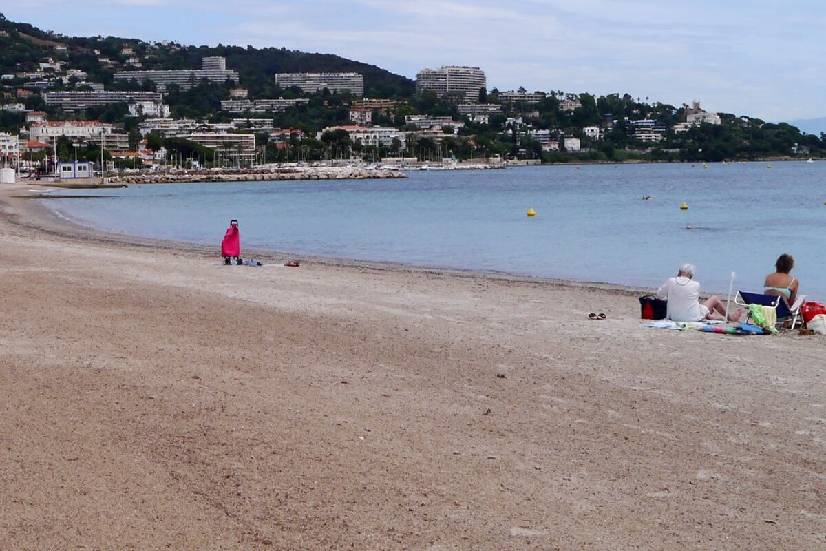image of a beach and the sea with people sitting on sand