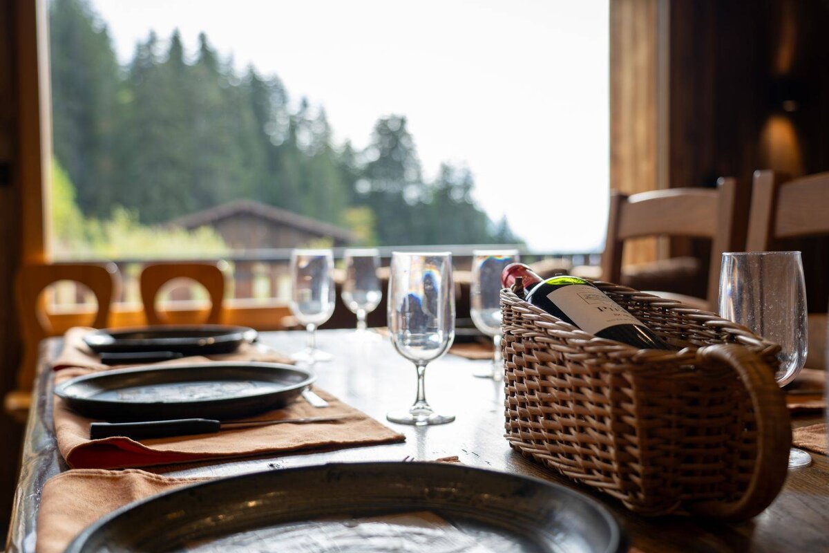 A bottle of wine sits in a basket on a table