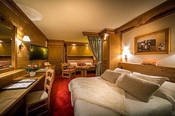 A hotel room with a bed a desk and a television