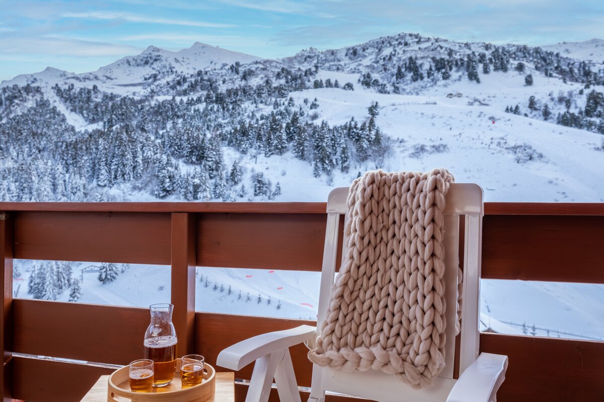 A bottle of beer sits on a table next to a chair
