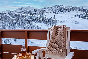 A bottle of beer sits on a table next to a chair