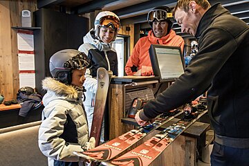 A man is adjusting a pair of skis that say rossignol on them