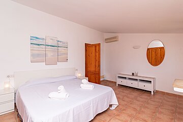 A bedroom with a large bed and a mirror