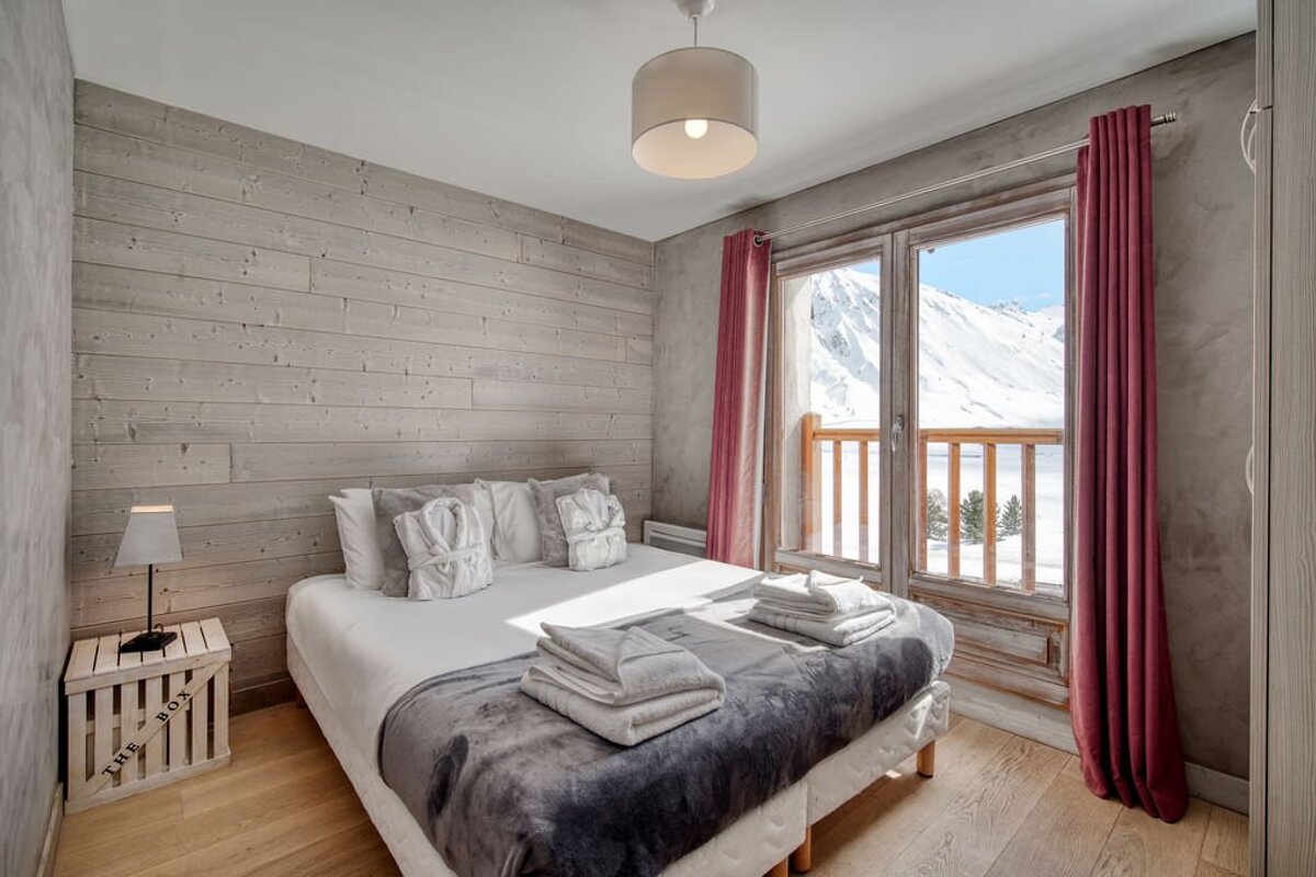 A bedroom with a bed and a window with mountains in the background