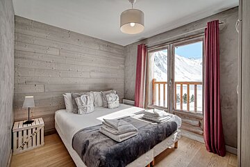 A bedroom with a bed and a window with mountains in the background