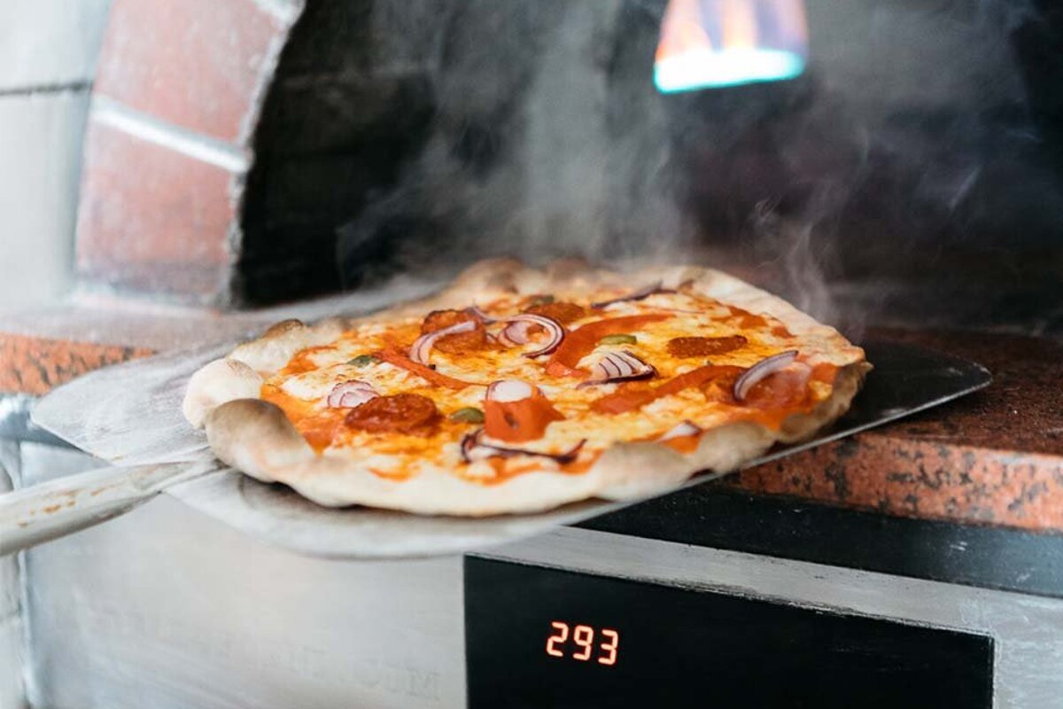 A pizza is being taken out of the oven and the digital display reads 293