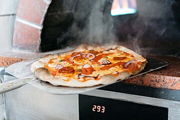 A pizza is being taken out of the oven and the digital display reads 293