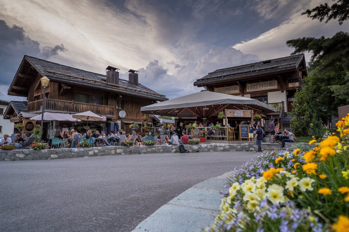 A group of people sit outside of a restaurant called le chalet village
