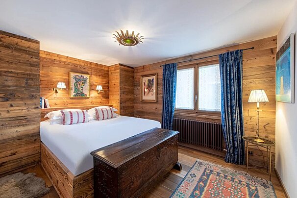 A bedroom with wood paneling and a large bed