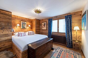 A bedroom with wood paneling and a large bed