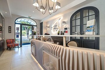 A hotel lobby with a desk and chairs and a sign on the wall that says la maison de provence