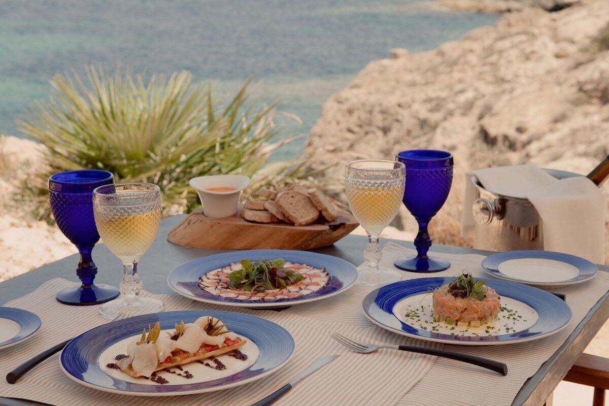 A table with plates of food and wine glasses on it