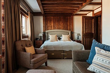 A bedroom with a large bed and a chair