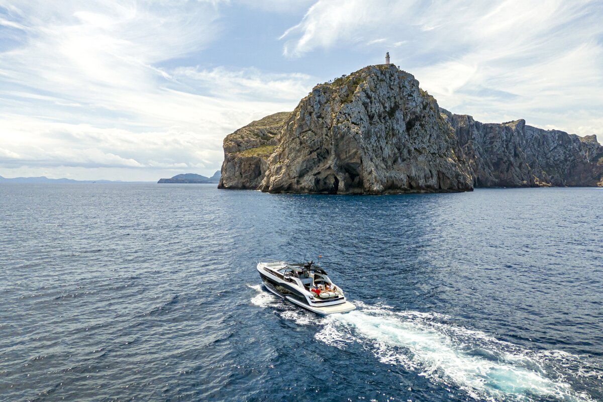 A boat in the ocean with a lighthouse in the background