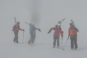 four skiers in fog