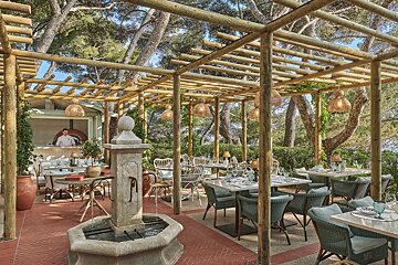 A restaurant with tables and chairs under a wooden pergola