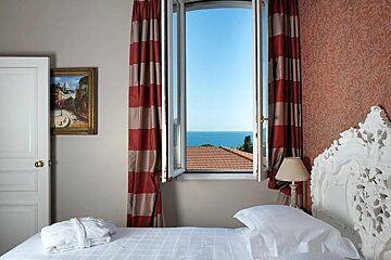 A bedroom with a bed and a window with a view of the ocean