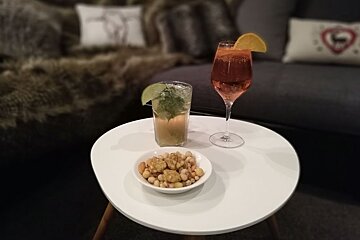 A white table with nuts and a drink on it