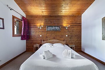 A bedroom with wood paneled walls and a bed
