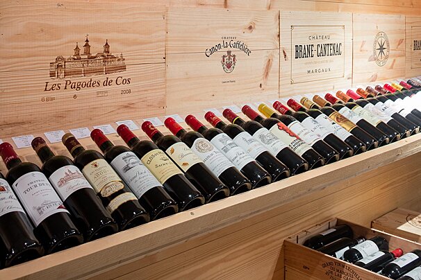 Many bottles of wine are lined up on a shelf including les pagodes de cos