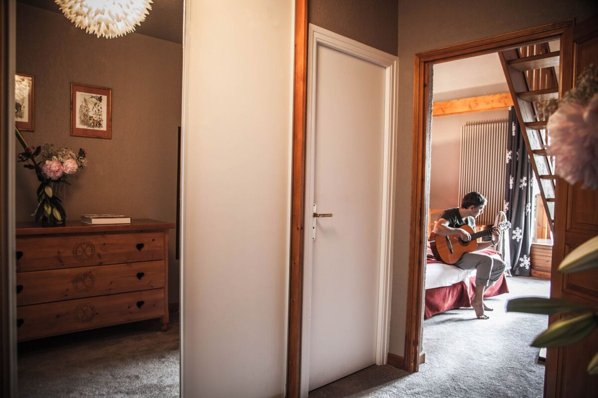 A woman sits on a bed playing a guitar