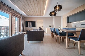 A living room with a dining table and chairs and a flat screen tv