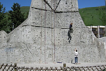 A person is climbing a rock wall with graffiti on it