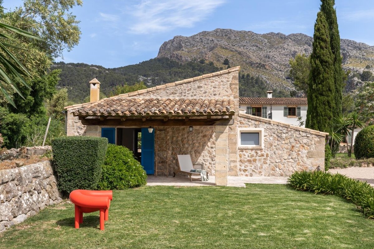 A small stone house with a blue door and a mountain in the background