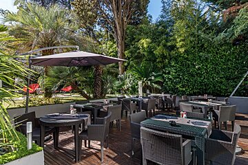 A patio with tables and chairs under an umbrella