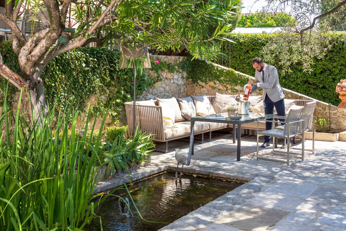 A man is pouring a drink into a glass on a patio