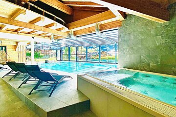 A large indoor swimming pool with a jacuzzi next to it