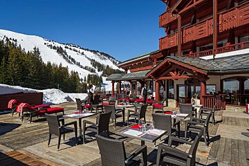 Tables and chairs outside of a building with a mountain in the background