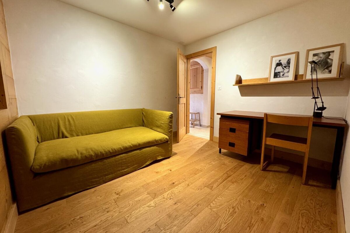 A small room with a yellow couch and a desk