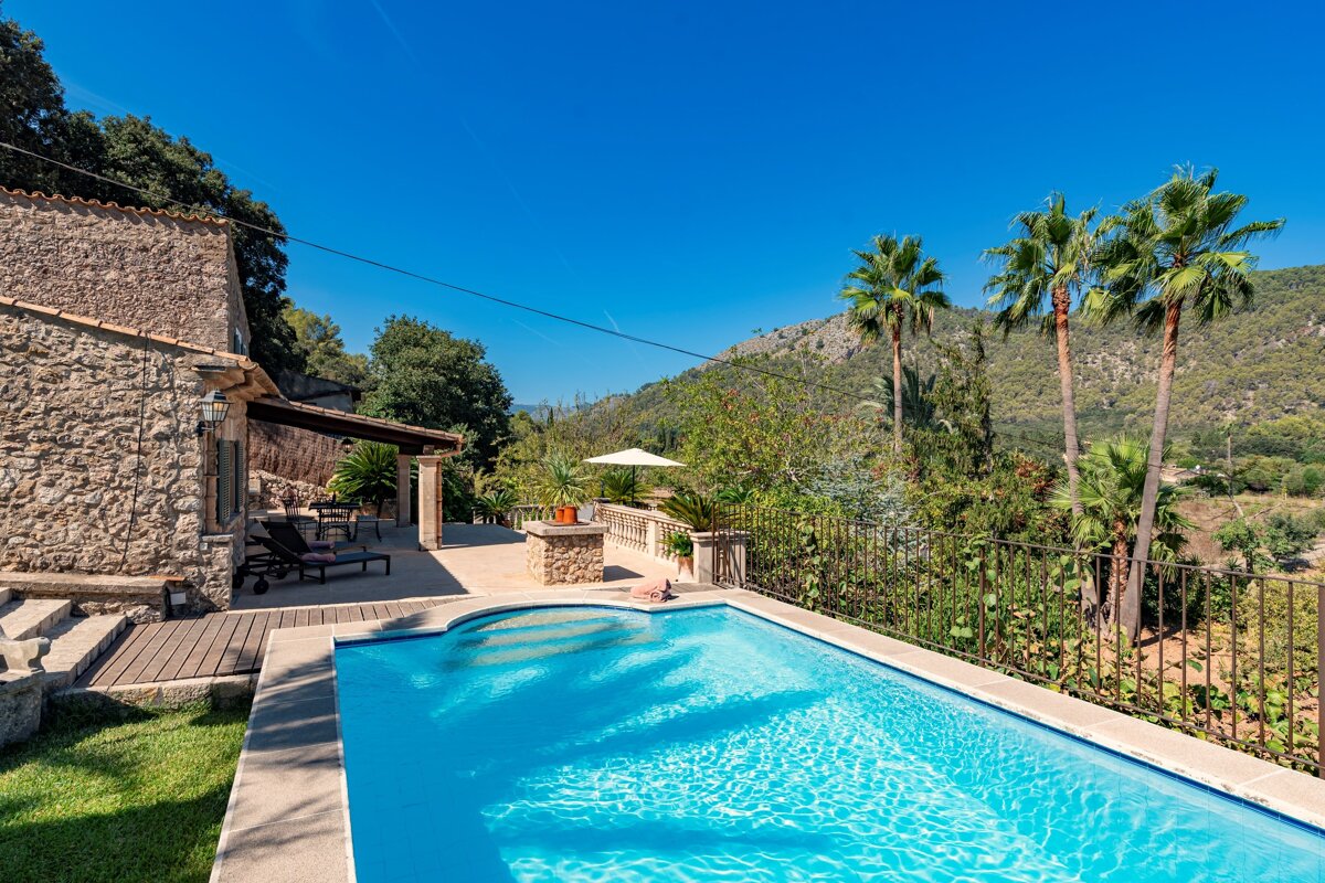 A large swimming pool in front of a stone house