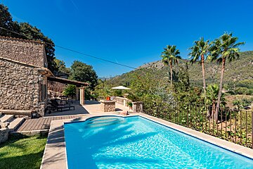 A large swimming pool in front of a stone house
