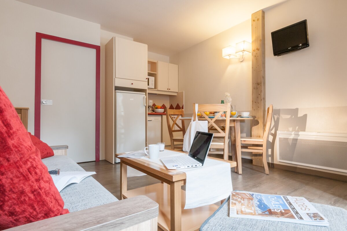 A living room with a laptop on a table and a magazine that says alpes