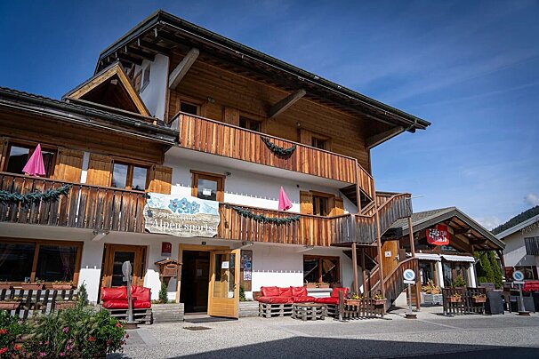 A traditional alpine building with white walls, wooden balconies, and a sign for