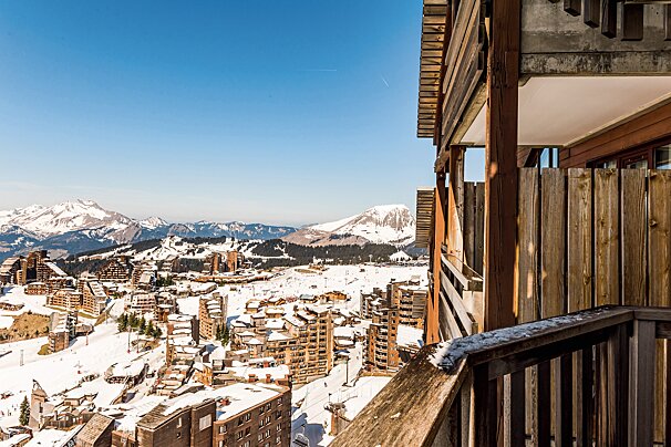 A balcony overlooking a snowy city with mountains in the background