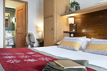 A bedroom with a wooden headboard and a red blanket with snowflakes on it