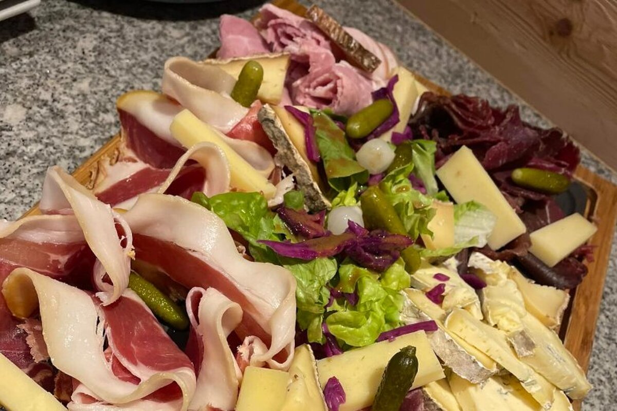 A variety of meats and cheeses on a wooden cutting board