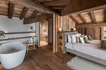 A bedroom with a bathtub and a bed