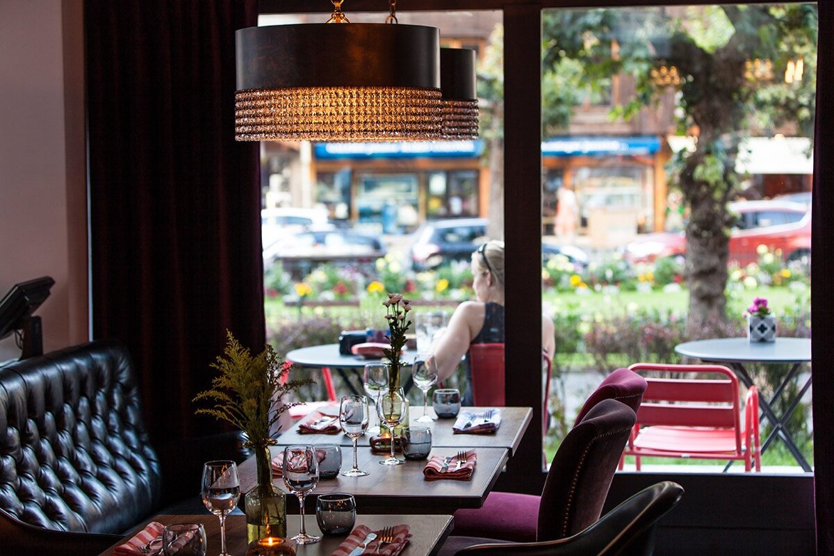 A woman sits at a table in a restaurant looking out the window