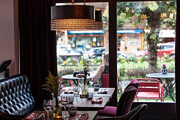 A woman sits at a table in a restaurant looking out the window