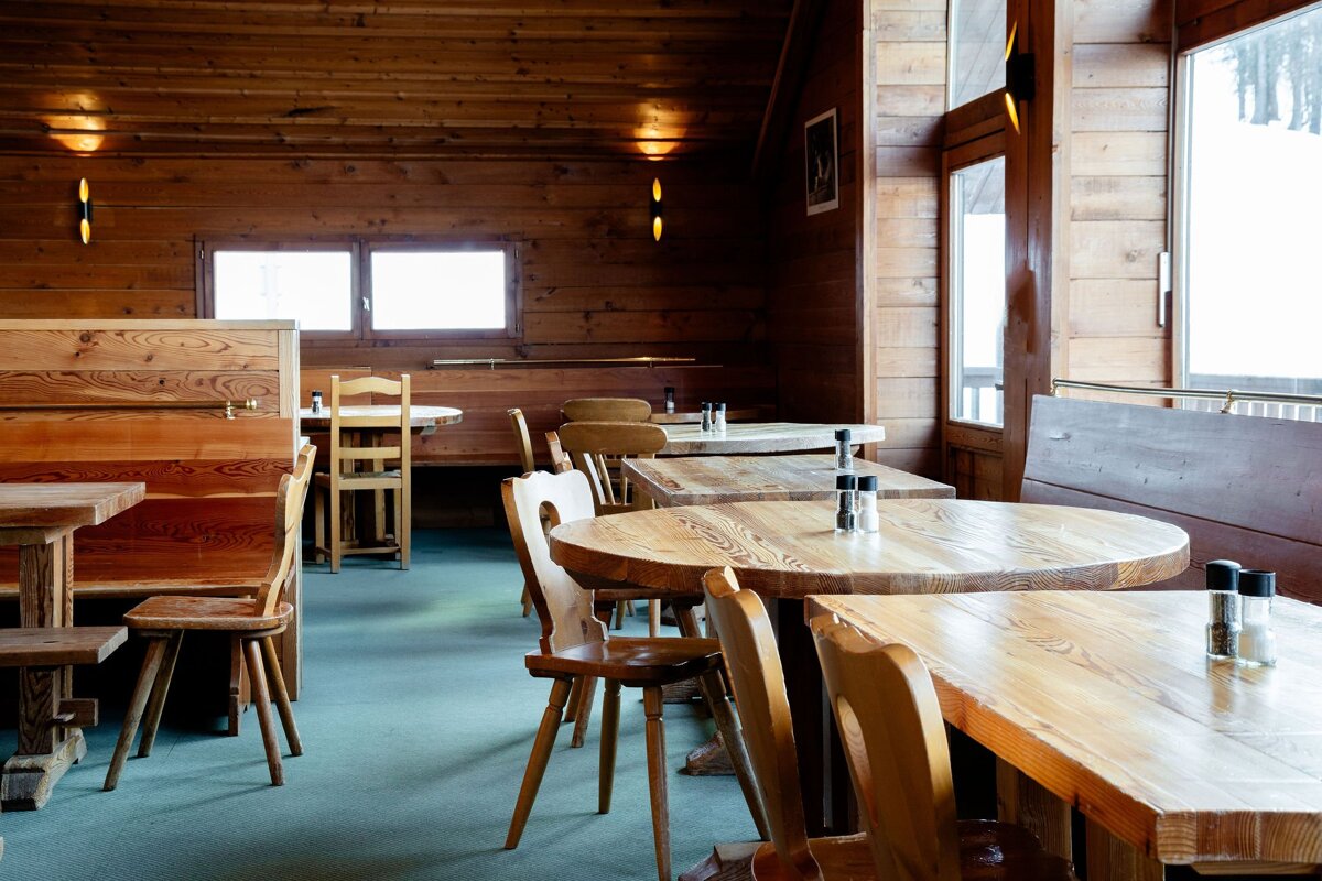 A restaurant with wooden tables and chairs with salt and pepper shakers on them