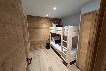 A bunk bed in a room with a wooden wall
