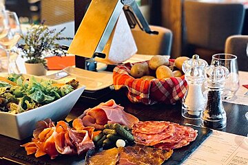 A tray of meats and vegetables sits on a table next to a menu