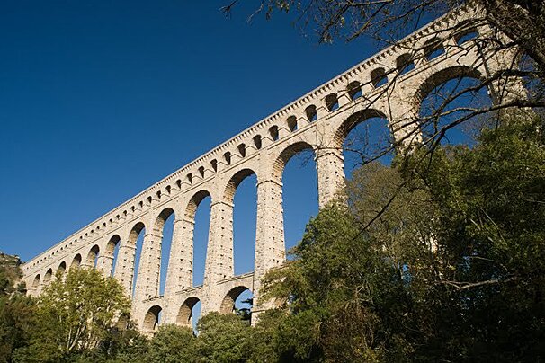 A very long stone bridge with arches surrounded by trees