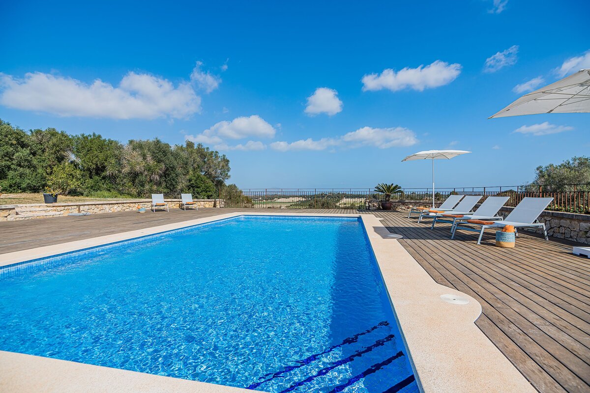 A large swimming pool with chairs and umbrellas around it