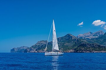 A sailboat in the ocean with mountains in the background